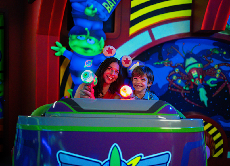 Woman and child using interactive blasters on Buzz Lightyear's Space Ranger Spin
