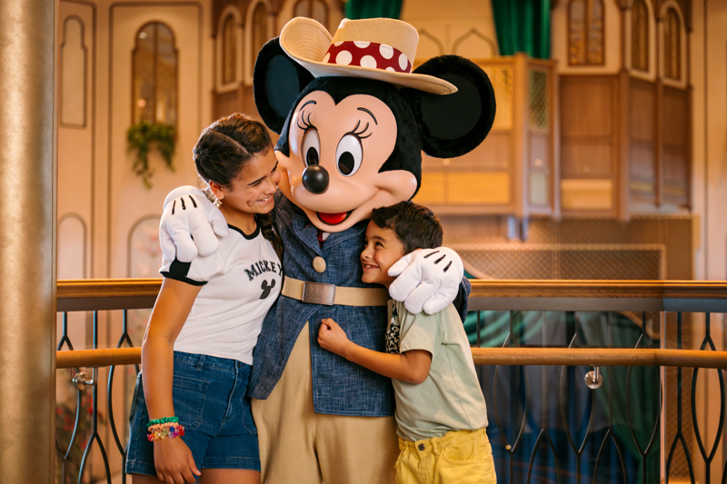 Two happy children hugging Minnie aboard the Disney Treasure cruise