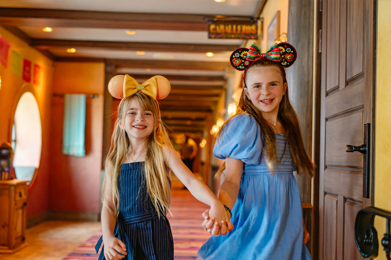 Two happy girls holding hands aboard Disney Treasure