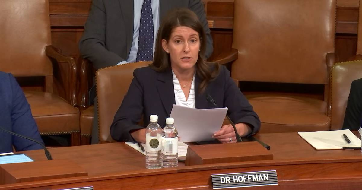 A smiling woman gently holds the hand of an elderly man